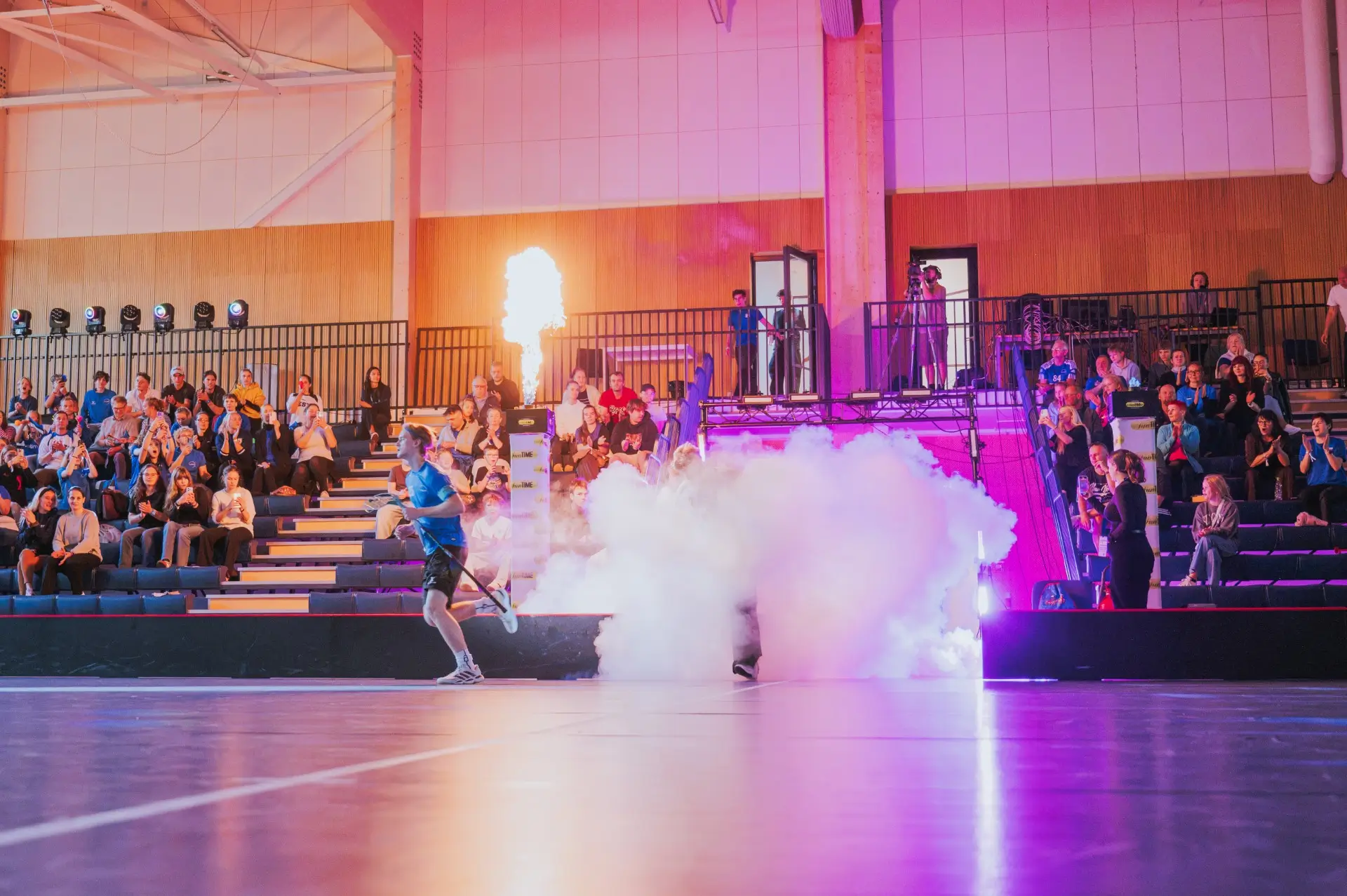 A floorball player enters the court in front of spectators.